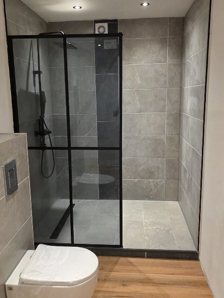 Fertiges Bad: bodengleiche Dusche mit schwarzer Glaswand, Wand-WC und Vinylboden in Holzoptik