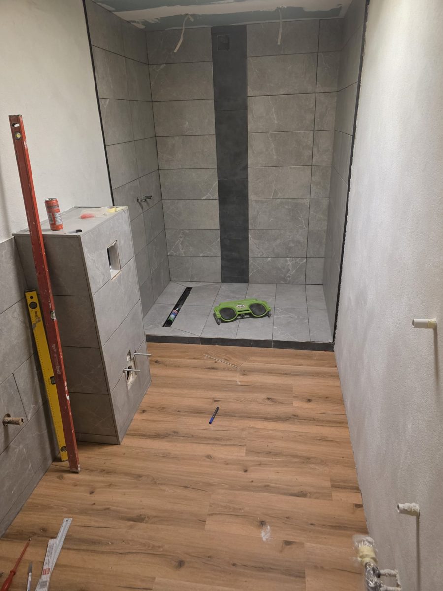 Badezimmer während der Sanierung: Dusche wird gefliest, Vinylboden frisch verlegt